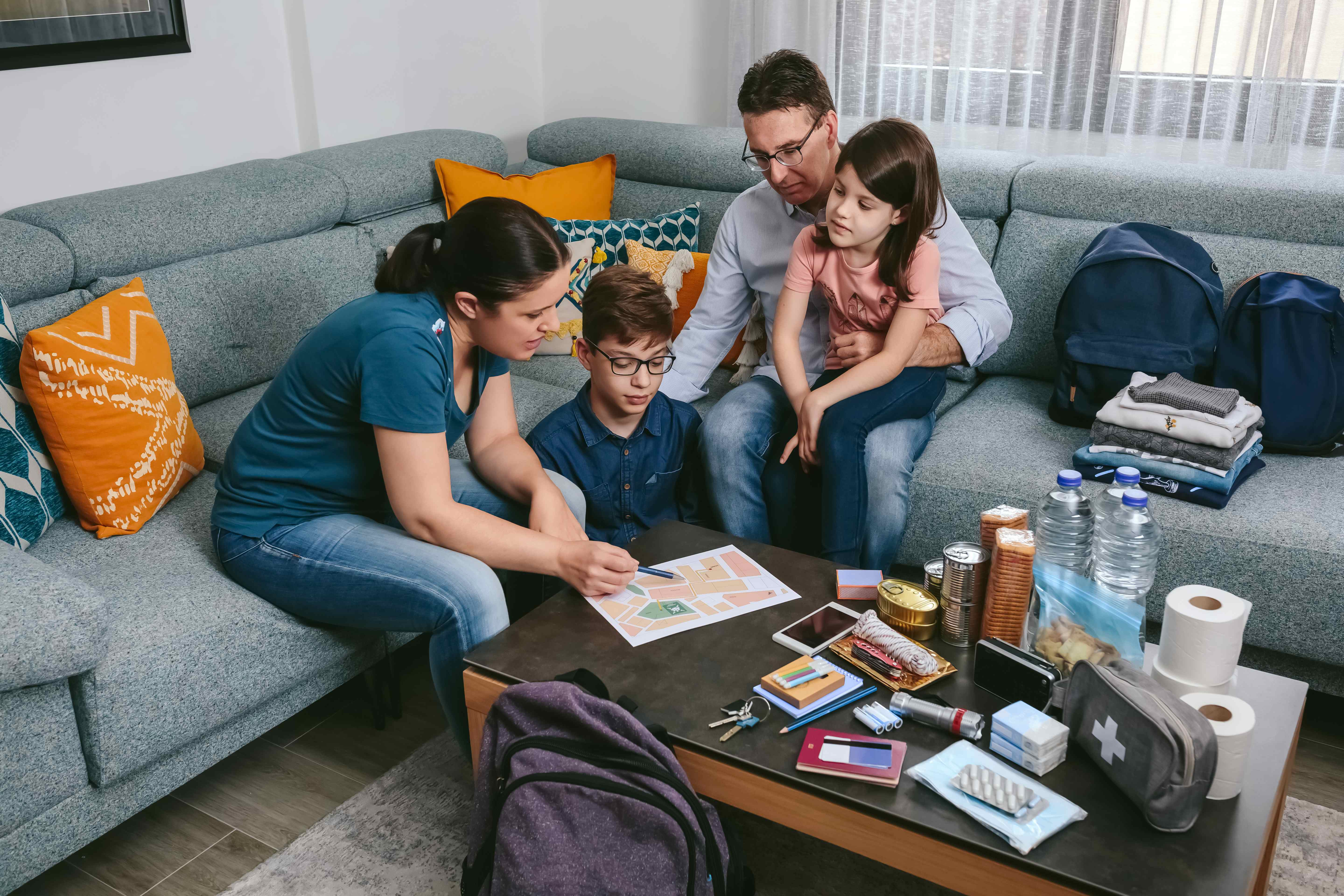 A family gathered around a coffee table with emergency preparedness supplies